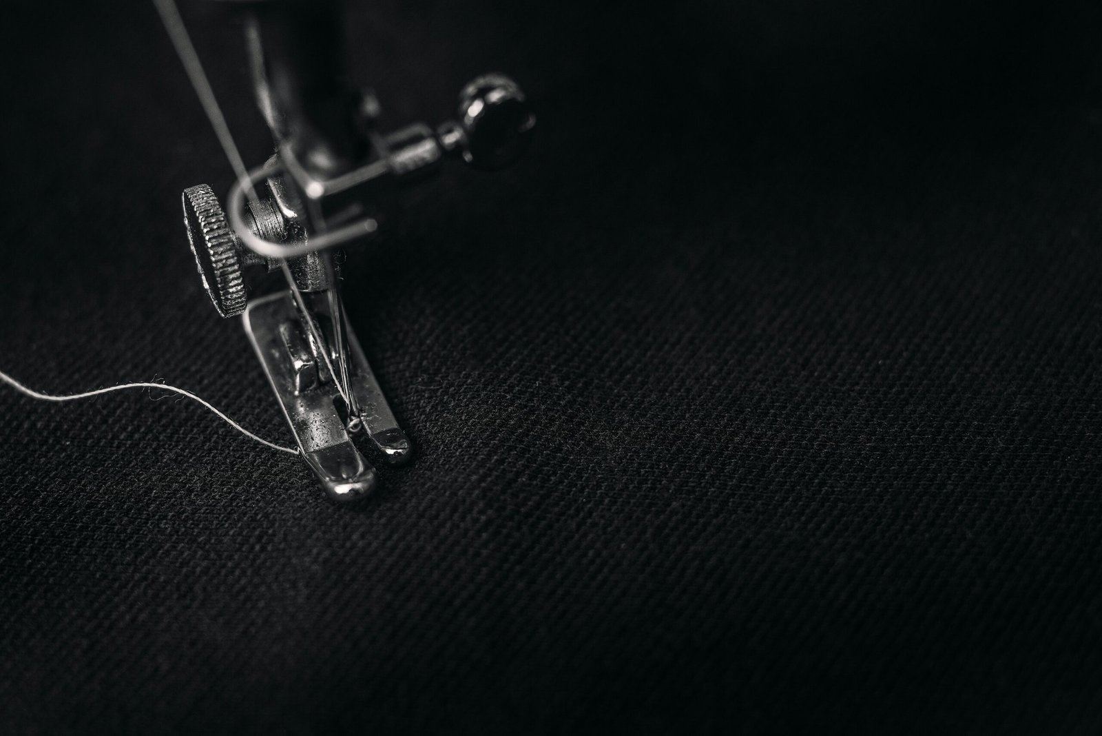 Detailed view of a sewing machine needle stitching fabric, highlighting sewing process and textile technology.